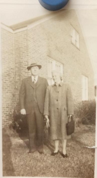 Two people outside the house. Perhaps Bud and Thelma Davis